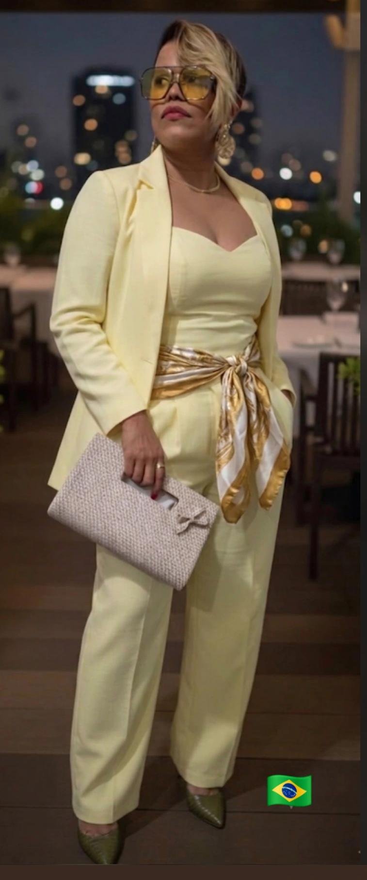 A mentora de estilo Karina Santos veste um conjunto monocromático de alfaiataria em tom amarelo suave, combinando óculos cosméticos e uma clutch.